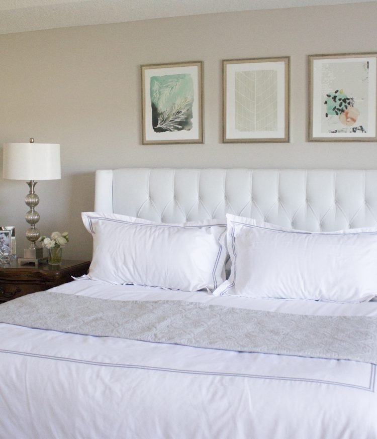 white headboard with art prints above the headboard