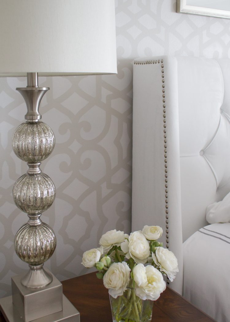 stenciled wall behind white upholstered headboard