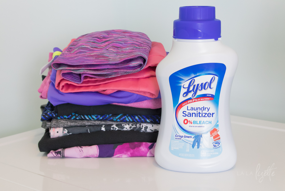 Lysol Laundry Sanitizer next to folded gym clothes