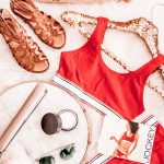 A flatlay display of festival staple sandals, flat iron, sunglasses, moisturizer, and red retro Jockey underwear with a straw bag that reads "cabana boy wanted"