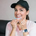 smiling woman blotting excess oil from her face with oil blotting sheets