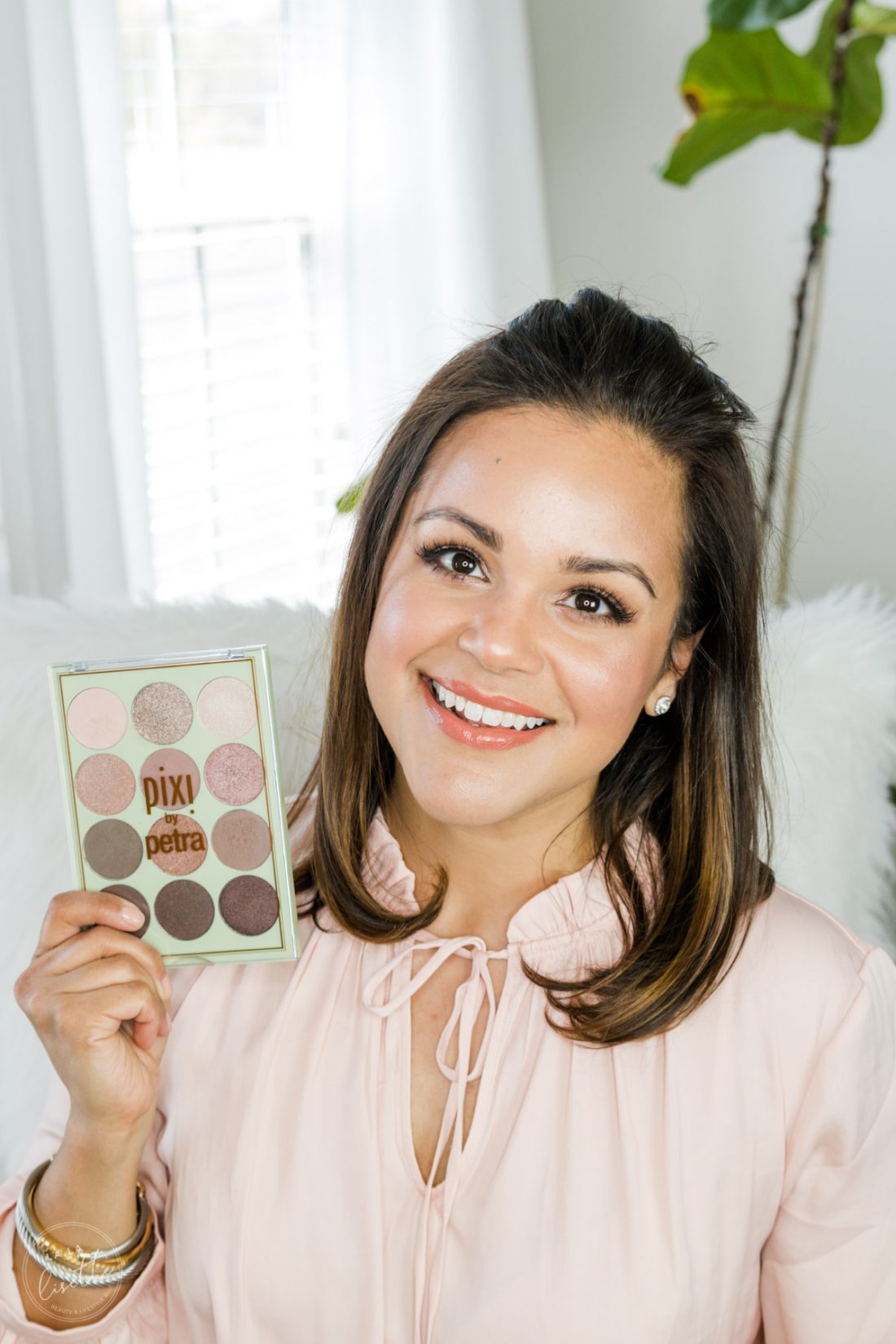 Beauty blogger with glowing spring makeup holding Pixi by Petra eyeshadow palette