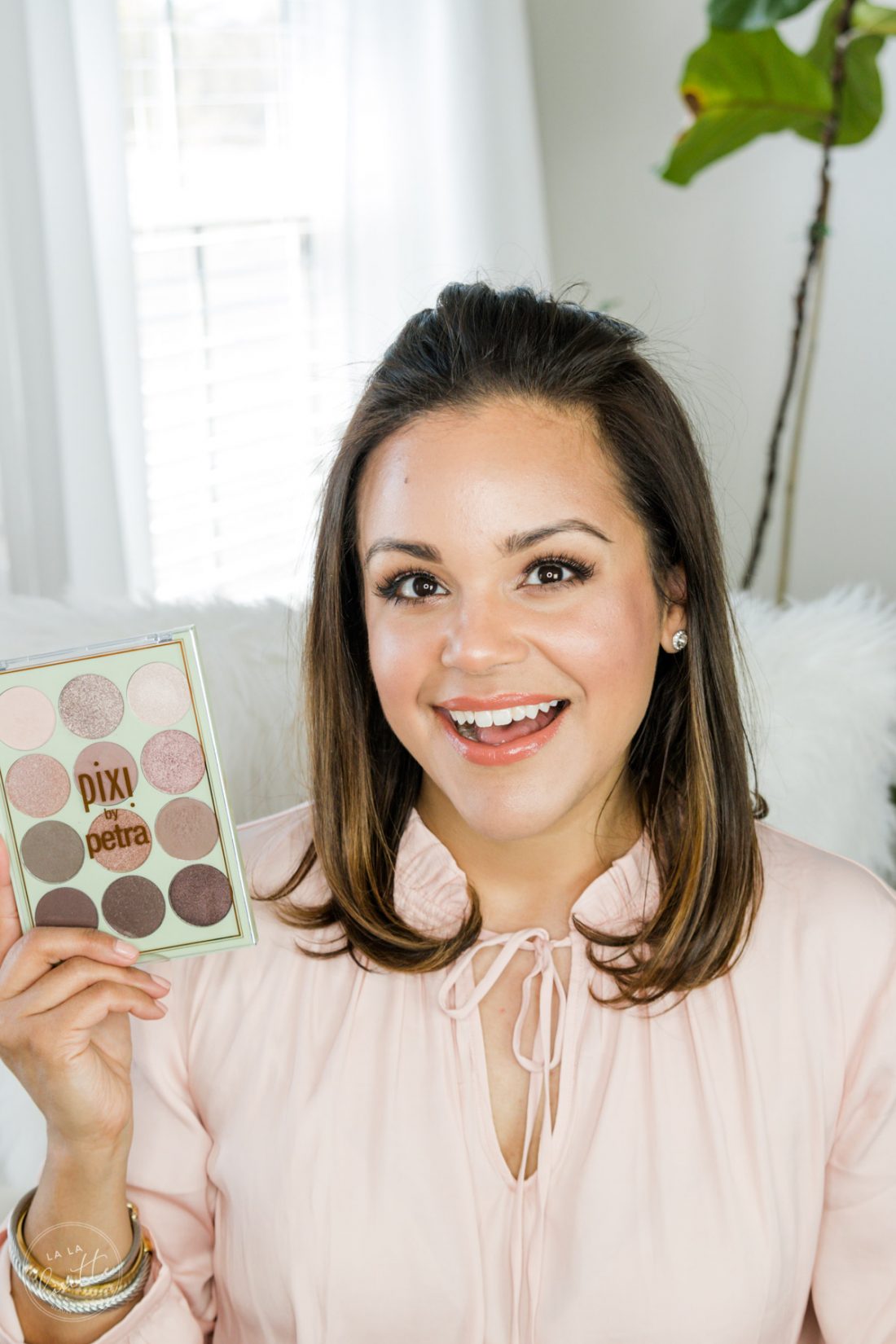 Beauty blogger with glowing spring makeup holding Pixi by Petra eyeshadow palette